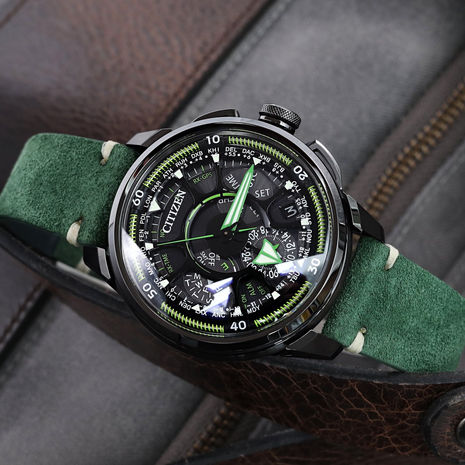 A watch with a green leather strap